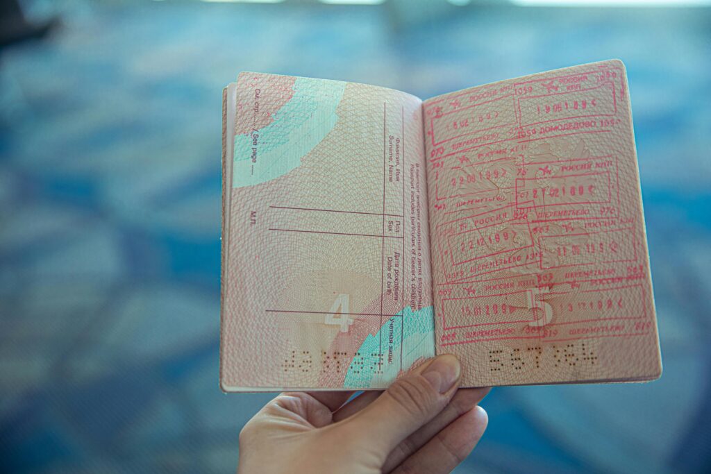 Close-up view of an open passport displaying various travel stamps in an airport setting.